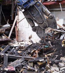 close up of a demolition claw working picking up debris in the wreckage of a destroyed building