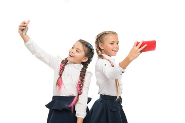 True selfie stars. Happy small schoolgirls taking selfie with smartphones isolated on white. Little children smiling to selfie cameras in mobile phones. Enjoying selfie session on september 1