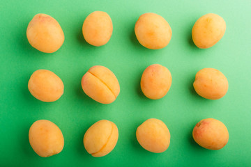 Rows of apricots on a green pastel background.