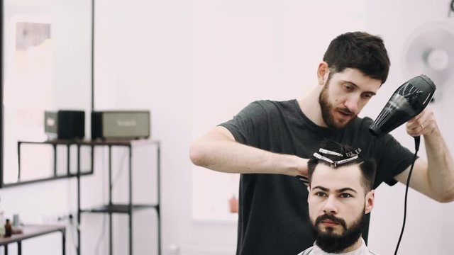 attractive man getting his hair slyled and blow dried after a haircut