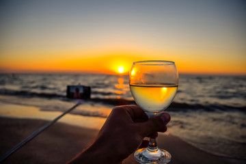 Selfie with selfie stick on the beach at sunset with a glass of champagne