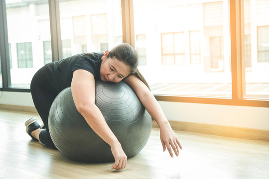 Fat Asian women are tired from exercising in fitness. Sleep hugging a yoga ball