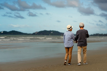 Life after retirement.Elderly life insurance.The old couple side by side until the old man.The elderly couple walk hand in hand on the beach to relax after long work.