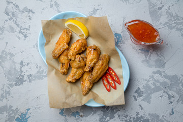 Chicken wings in sweet chili sauce on grey concrete table