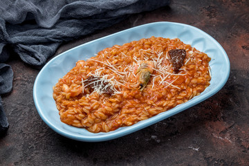 risotto with seafood on tomato sause on dark concrete rustic table
