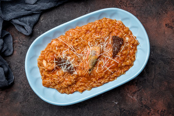 risotto with seafood on tomato sause on dark concrete rustic table