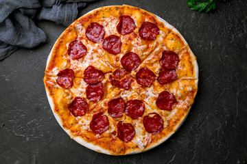 Pepperoni pizza on plate on black concrete table