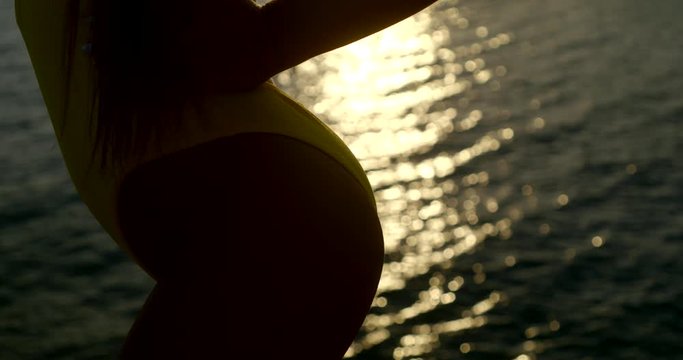 close-up side view on slender buttocks of woman dressed in swimsuit against ripple sea water