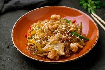 wok with shrimp and seafood on black concrete table