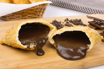 One open tradional Brazilian fried pastry called pastel stuffed with chocolate Brazilian dessert brigadeiro in a cutting board