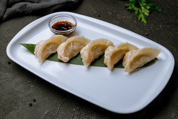 Chinese gedza with soy sauce on steam on black concrete table