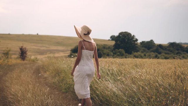 Young woman with hat walking trough the field
