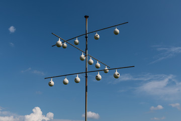 A purple martin gourd rack in front of a blue sky with white clouds.