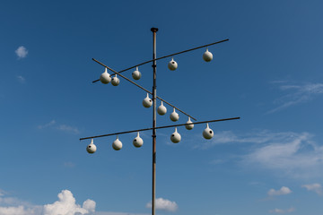 A purple martin gourd rack in front of a blue sky with white clouds.
