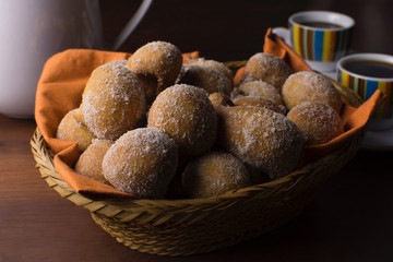Traditional Brazilian mini fried cakes called bolinho de chuva in a basket in wood breakfast table background close
