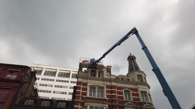 Construction workers in London at roof height in a cherry picker working