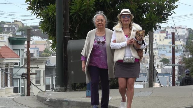 Senior mother and adult daughter crossing city street in San Francisco