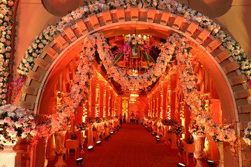 Luxurious indian wedding decoration entrance decorated with lighting and flowers, selective focus -...