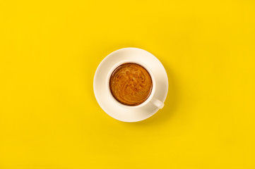 Cup of coffee o n yellow background.top view