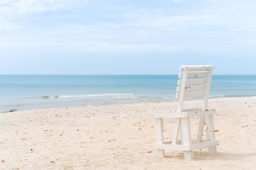 Vintage white wooden chair left on the beach.  The beautiful beach in Thailannd with beautiful blue sky and cloud background.