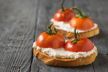 Two pieces of toasted bread with cottage cheese and tomatoes on the table.