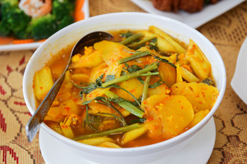 Traditional Thai spicy yellow soup with vegetable, bamboo shoot, meat, fish, seafood and spicy herb close up.