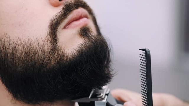 professional businessman getting his beard froomed and trimmed by a barber