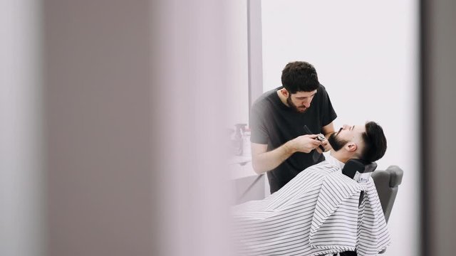 professional businessman getting his beard froomed and trimmed by a barber