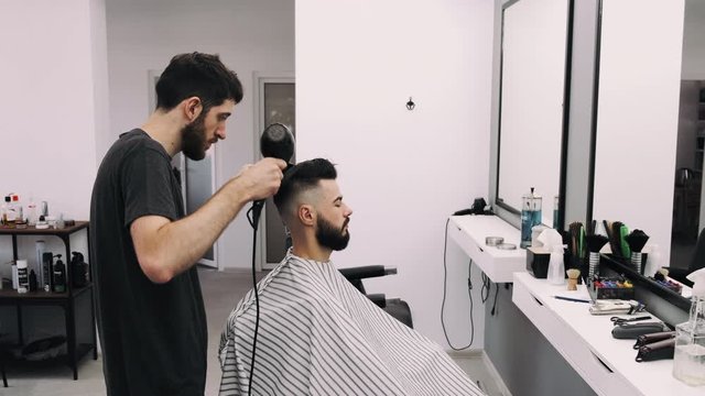 attractive man getting his hair slyled and blow dried after a haircut