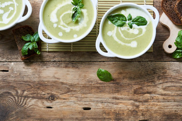 Zucchini cream soup with basil in white bowls 