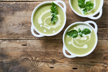 Zucchini cream soup with basil in white bowls 