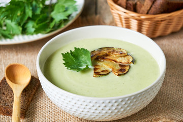 Soup puree with zucchini and greens in a white bowl  
