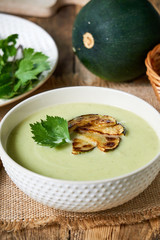 Soup puree with zucchini and greens in a white bowl  