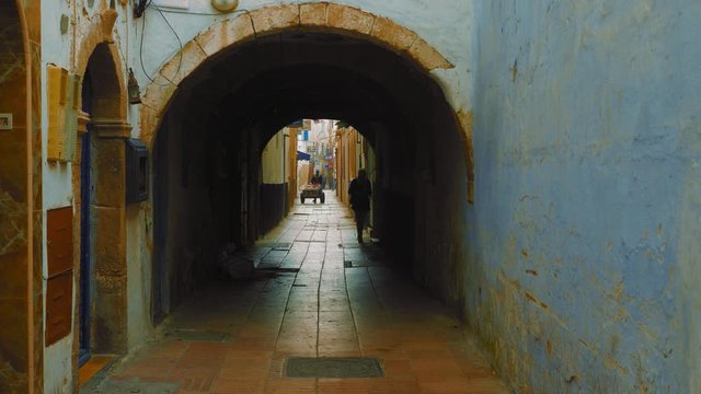 Silhouettes of people walking in narrow streets of old town medina in Essaouira