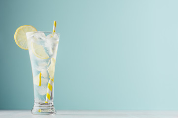 Homemade diet transparent lemonade with lemon, ice cubes, soda, yellow striped straw in misted...