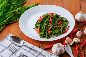 Stir fried morning glory placed on a wooden table.