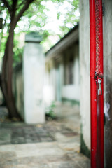 Selective focus on red steel frame of door with blurred glittering bokeh light and tree in background