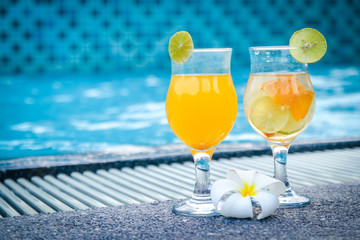 Two glasses of orange juice, along with plumeria flowers, are placed at the pool area on weekends.