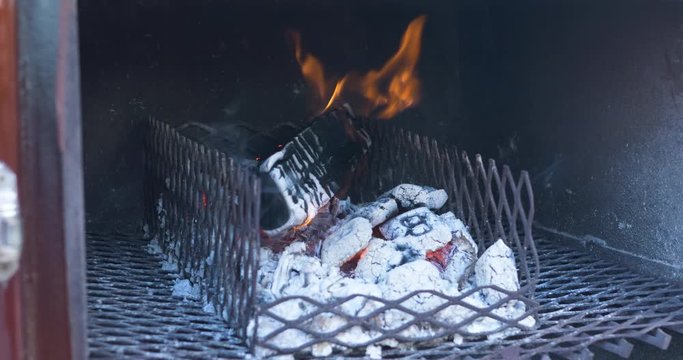 A log of wood and charcoal briquettes on fire in an off set smoker for BBQ. 4k