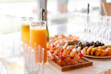 the buffet at the reception. Glasses of wine and champagne. Assortment of canapes on wooden board. Banquet service. catering food, snacks with cheese, jamon, prosciutto and fruit