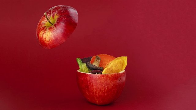 vegetable chips yellow potato purple carrot green radish green beans and shiitake mushrooms in hollow red apple red background plotagraph cinemograph