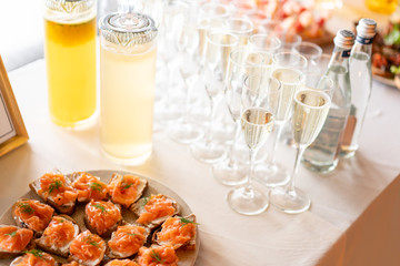 the buffet at the reception. Glasses of wine and champagne. Assortment of canapes on wooden board. Banquet service. catering food, snacks with cheese, jamon, prosciutto and fruit