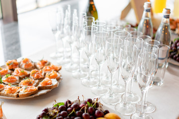 reception. Table top full of glasses of sparkling white wine with canapes and antipasti in the background. champagne bubbles