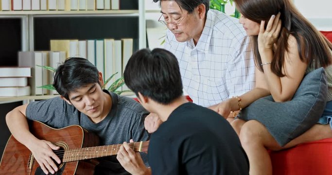 Happy Asian family playing guitar and singing a song together.