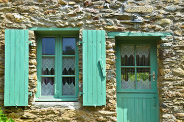 Sonniger Blick auf ein Fenster mit grünen Fensterläden und einer Hauswand aus Naturstein, in dem...