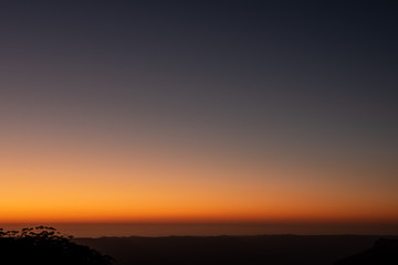 An orange sunrise over the Blue Mountains creates a beautiful silhouette of the foreground