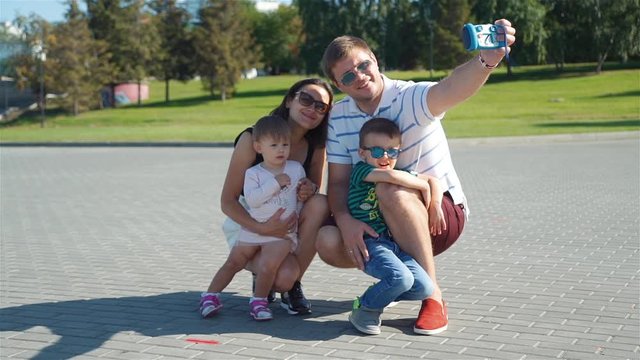 Cheerful Family Trying to Take Selfie with Toy Camera at the City Park in Summer Day. Slow Motion. Family, Childhood, Season, Technology and People Concept