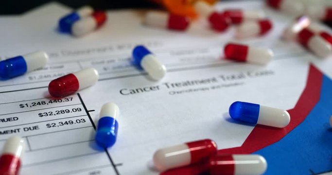 Expensive medicine, pills and cancer treatment drugs on a prop health insurance form showing high costs of cancer care.