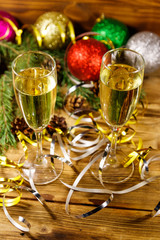 Two glasses of champagne and festive Christmas decorations on wooden table. Christmas and New Year celebration