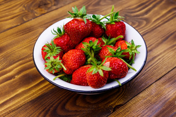 Fresh ripe strawberry in white bowl on a wooden table